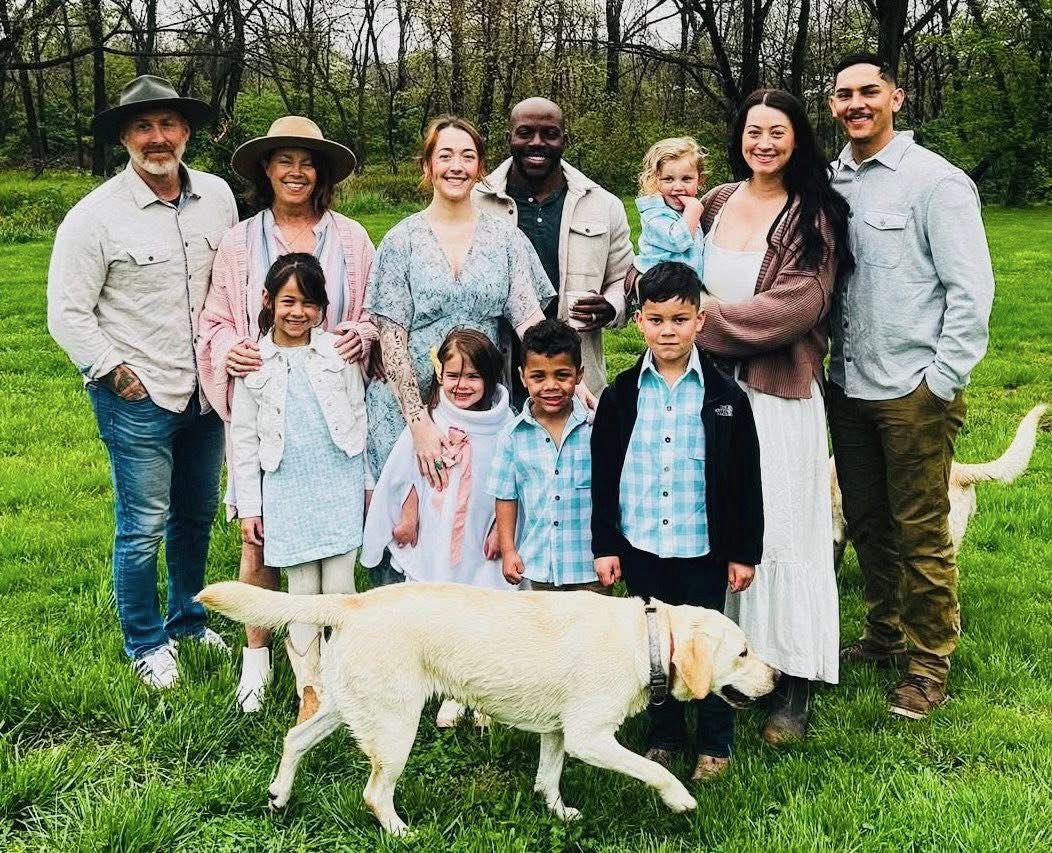Hugh and Cheryl Halter with their family on the lawn, their yellow lab wandering past